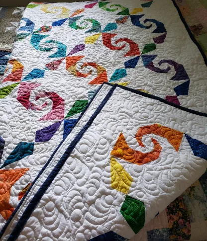 Free-motion quilting detail on handmade Storm At Sea pattern with bright rainbow cotton fabrics