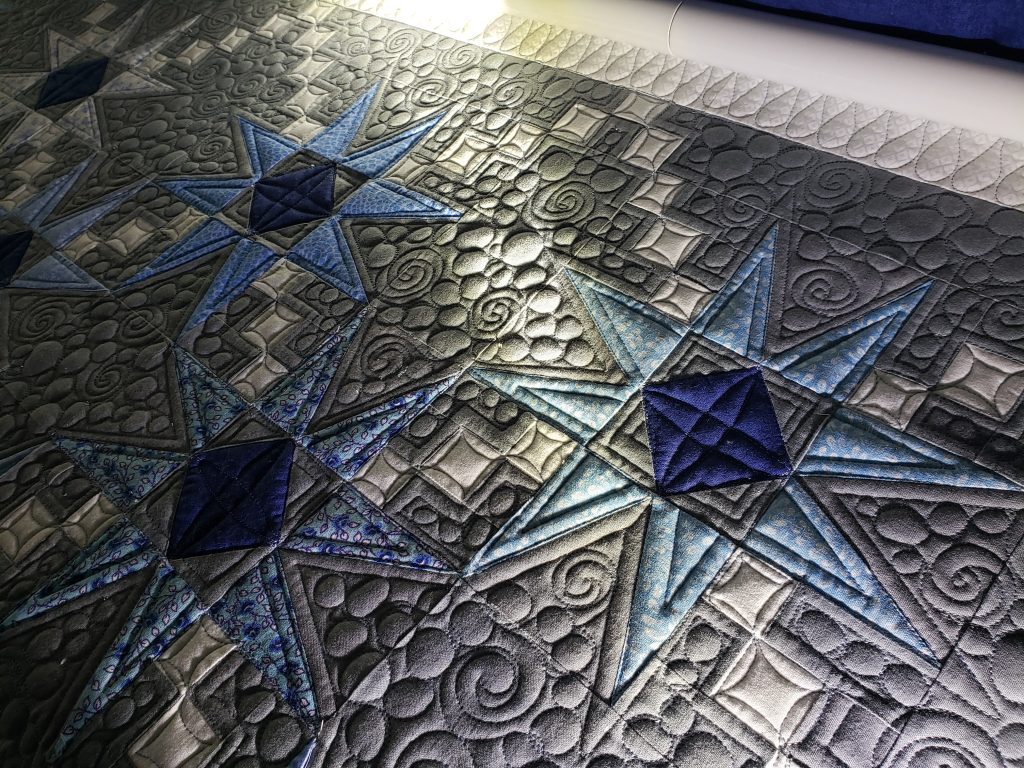 Detailed stitching on a homemade Hunter’s Star quilt in blue prints