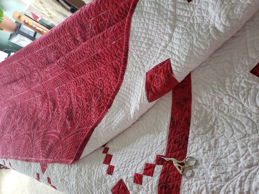 Mini Irish Chain quilt in red and white, folded on a chair