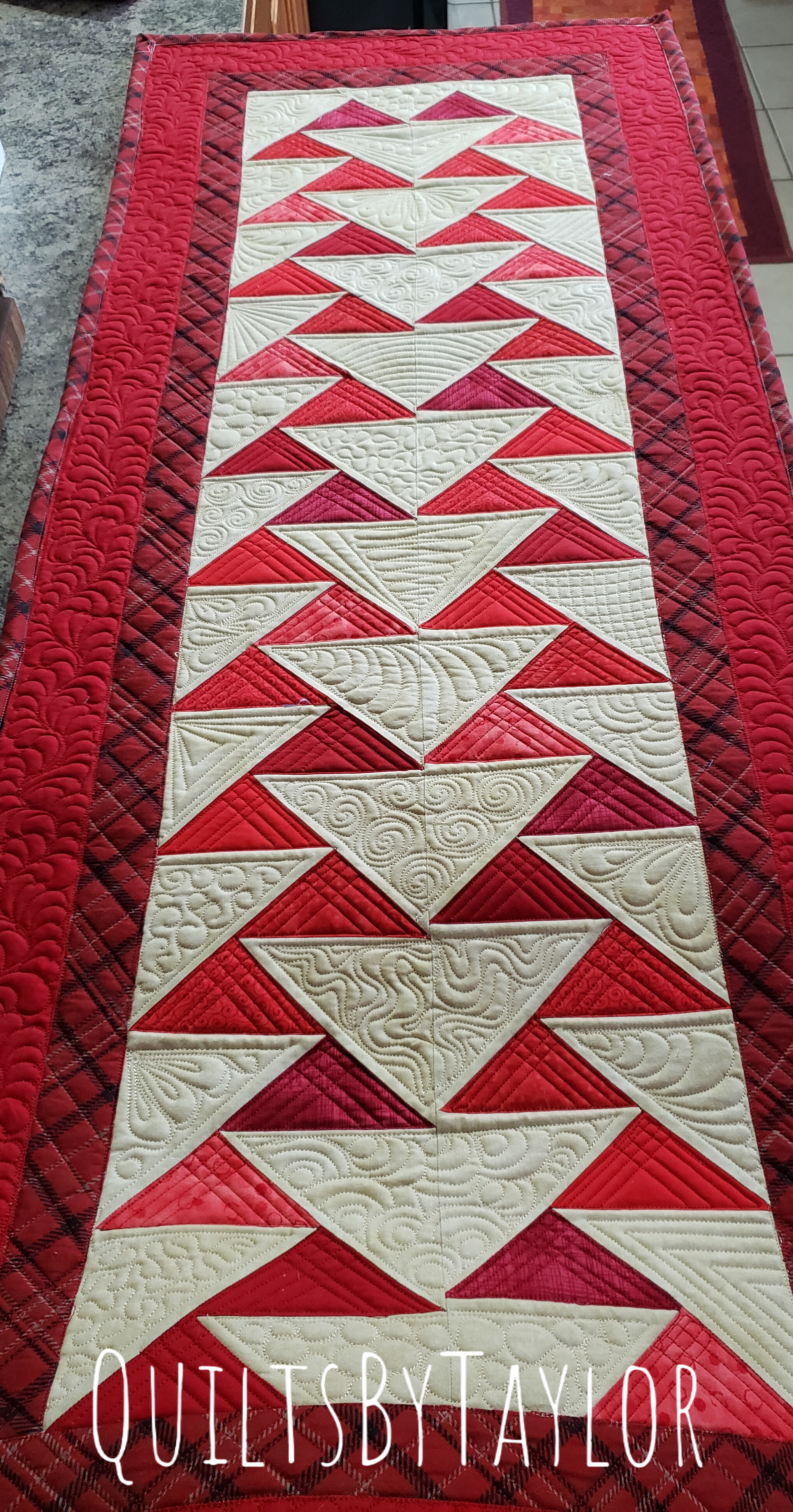 Handmade Quilts/ Close-up of red, Flying Geese quilt blocks with detailed free-motion quilting stitches.