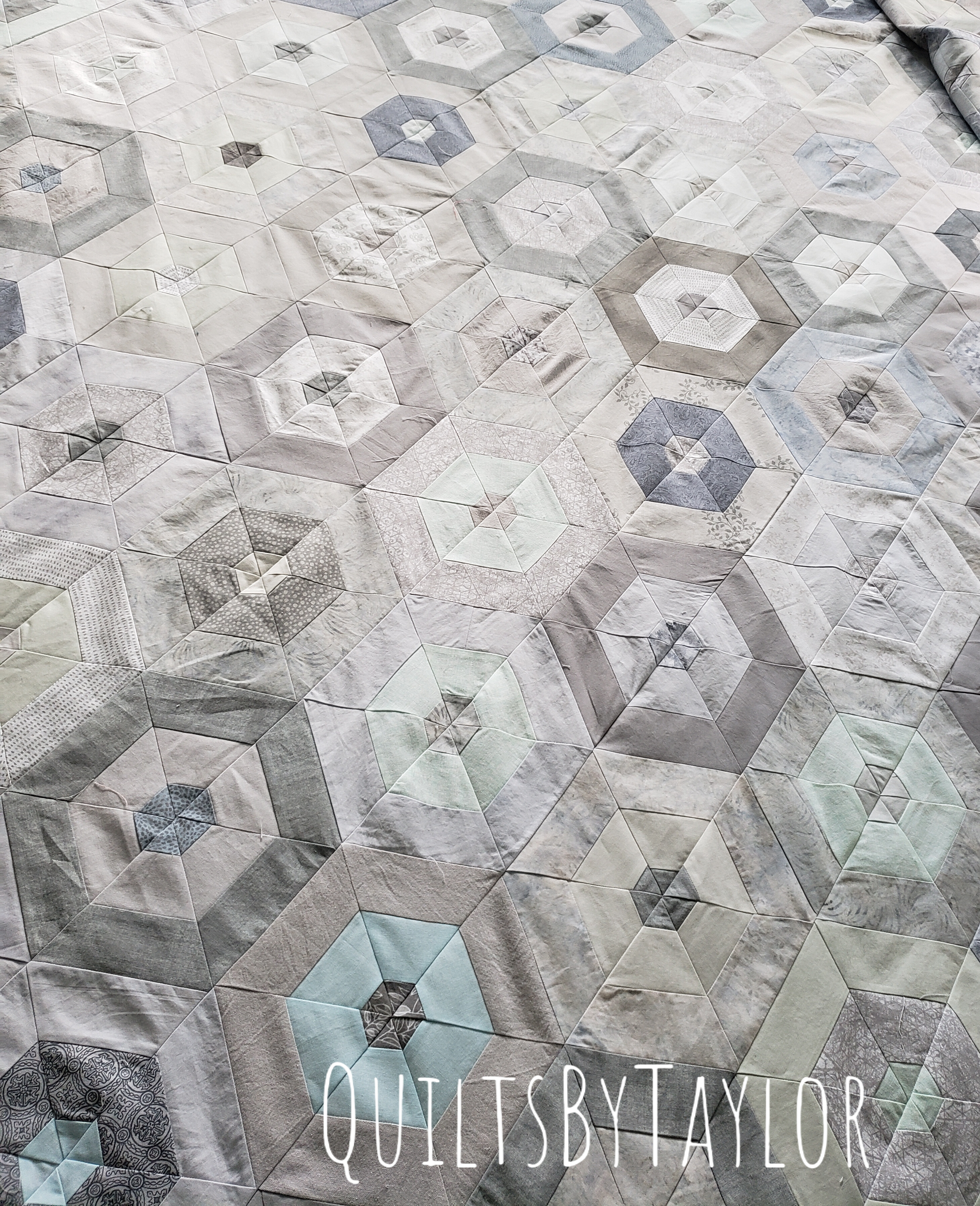neutral cotton patchwork quilt top laid out before quilting process begins
