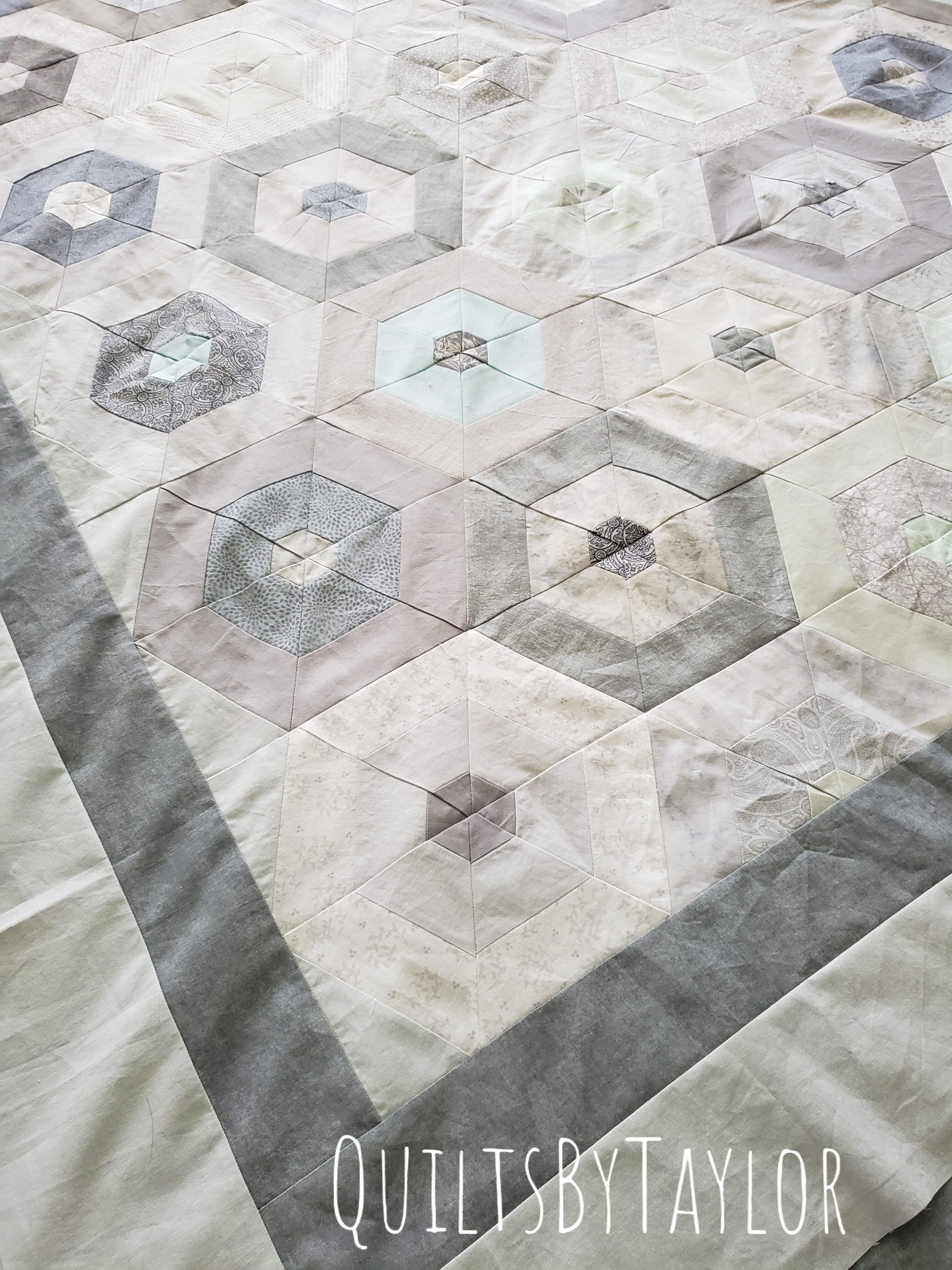 handmade neutral patchwork hexagon quilt top with soft gray border in progress
