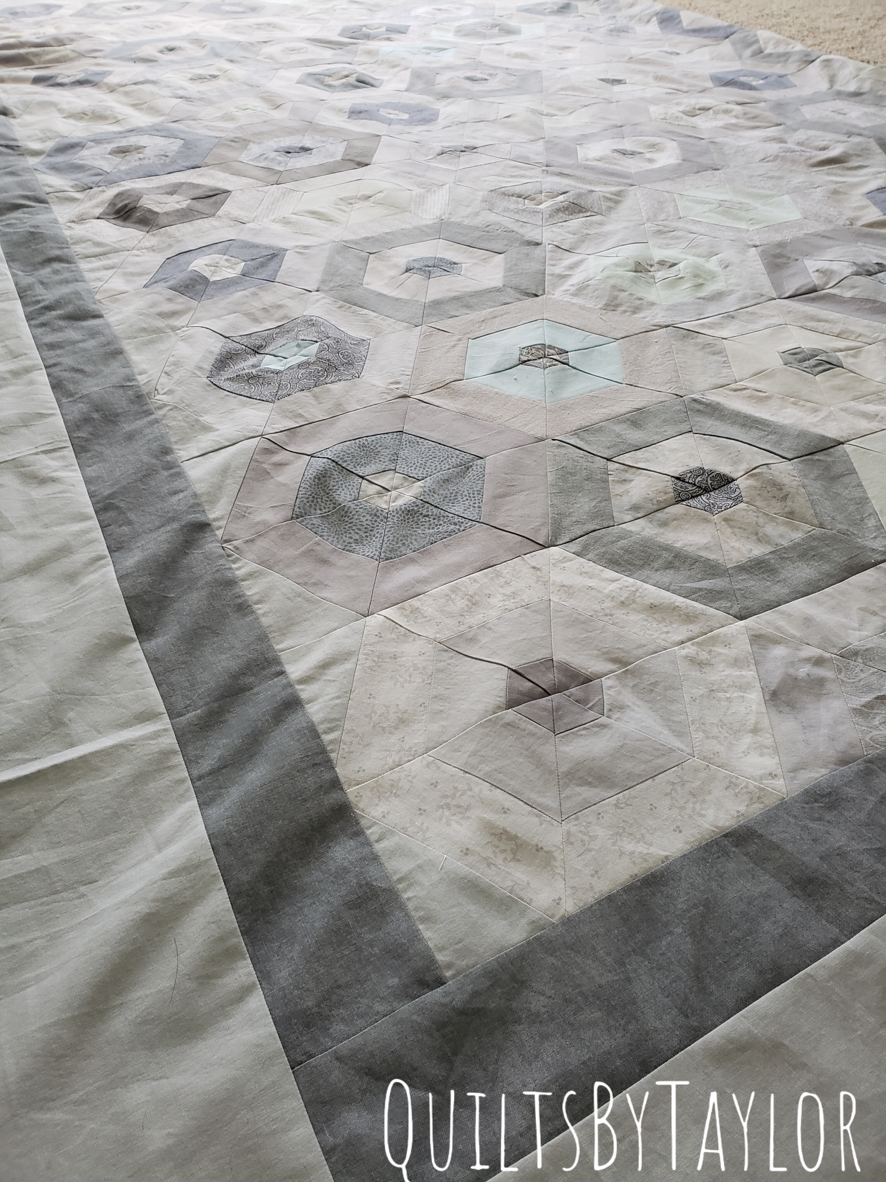close up of handmade patchwork quilt blocks with hexagon pattern in gray and cream tones