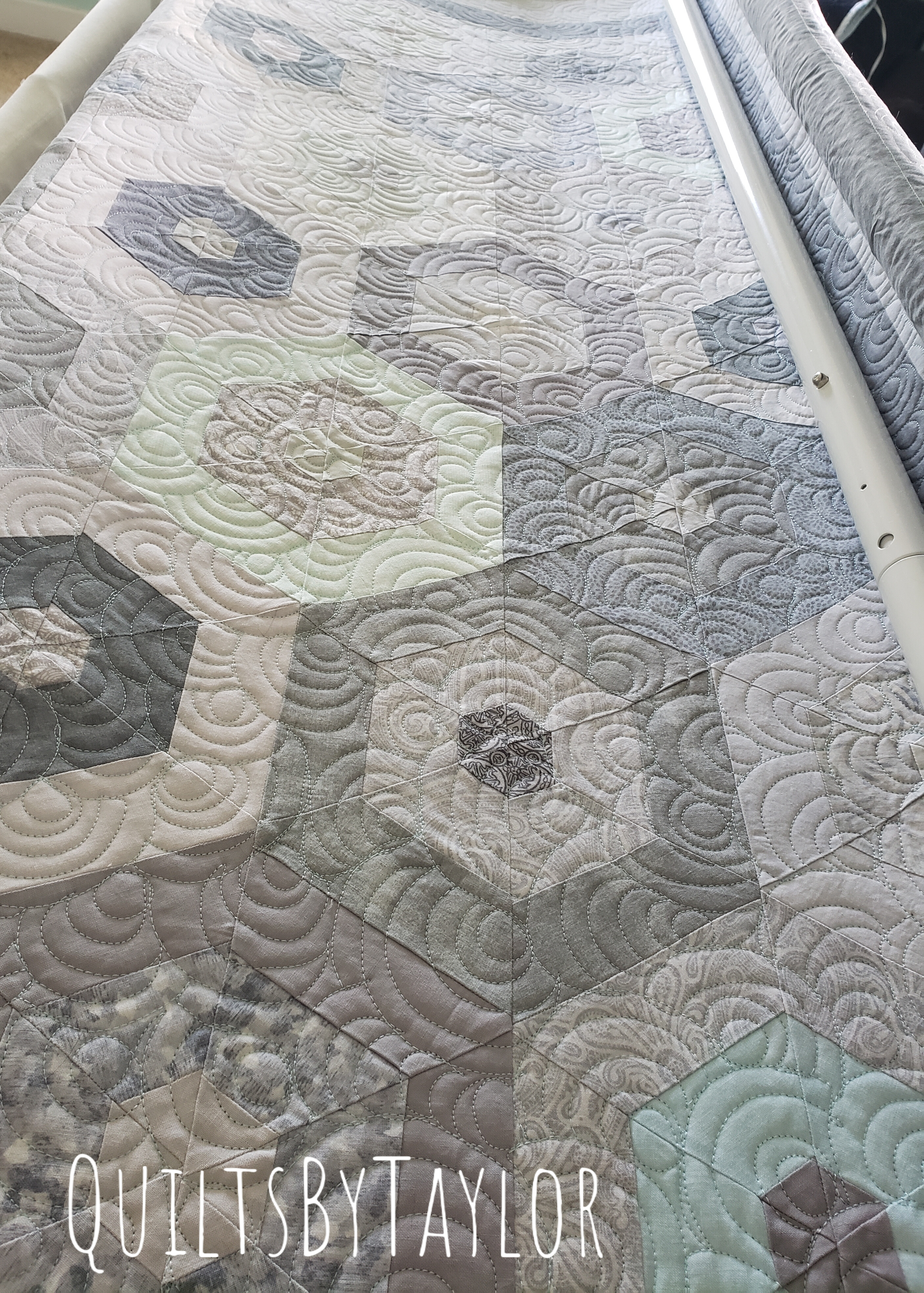 custom neutral cotton quilt loaded onto quilting machine during quilting process