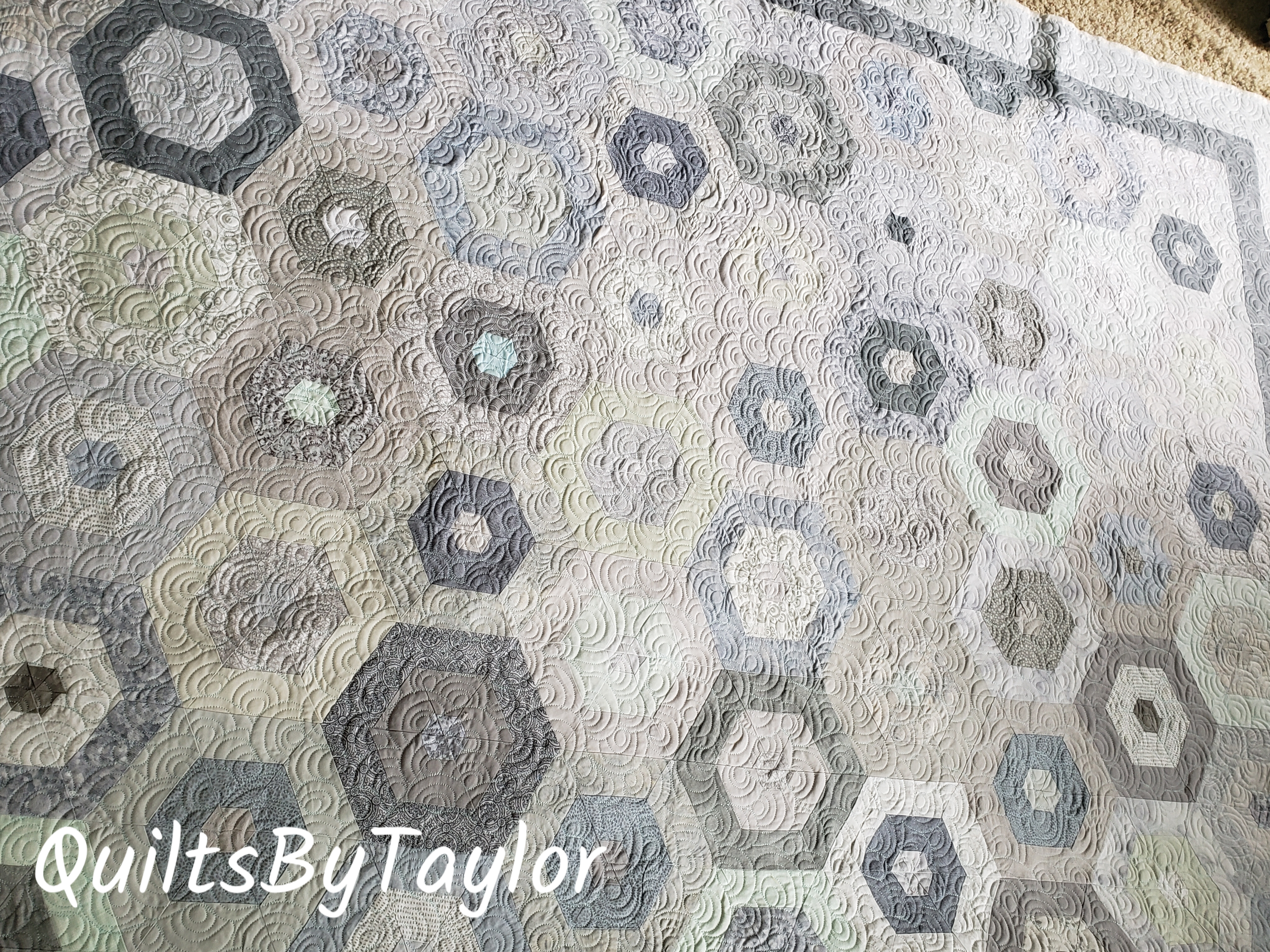 large handmade hexagon quilt in gray and cream colors finished with detailed quilting
