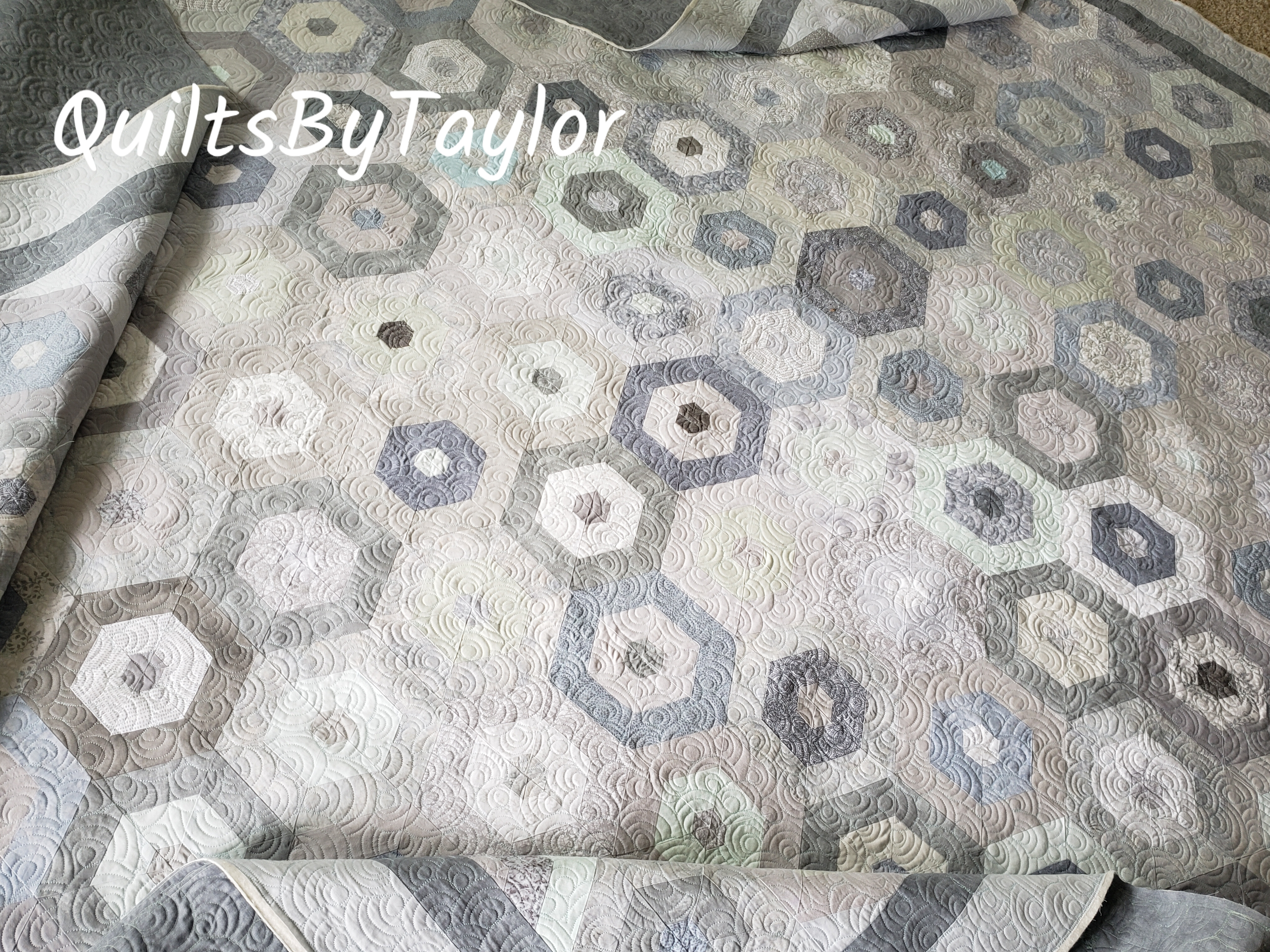 large handmade hexagon quilt in gray and cream colors finished with detailed quilting