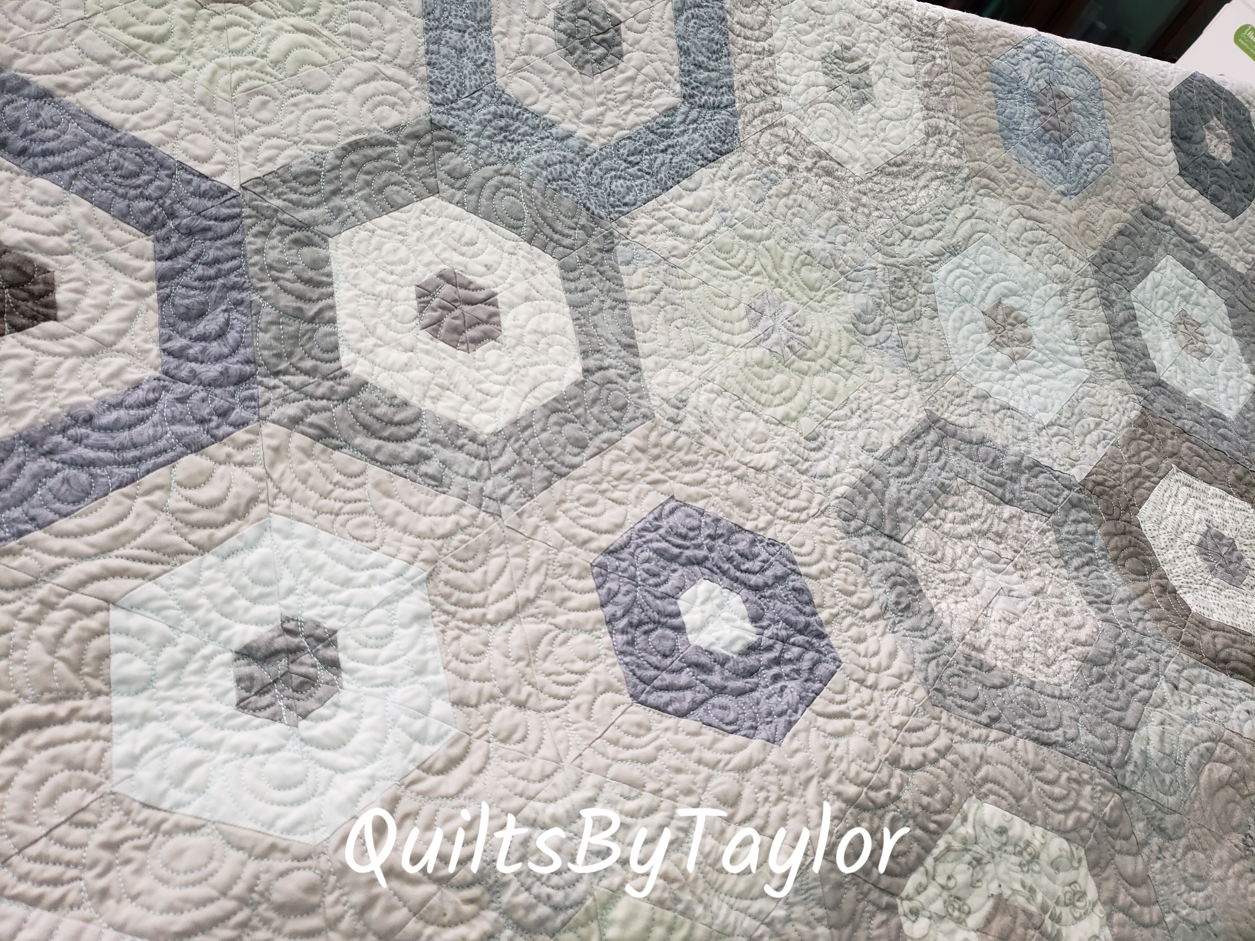 close up of dense quilting texture on handmade gray hexagon quilt with tone on tone fabrics