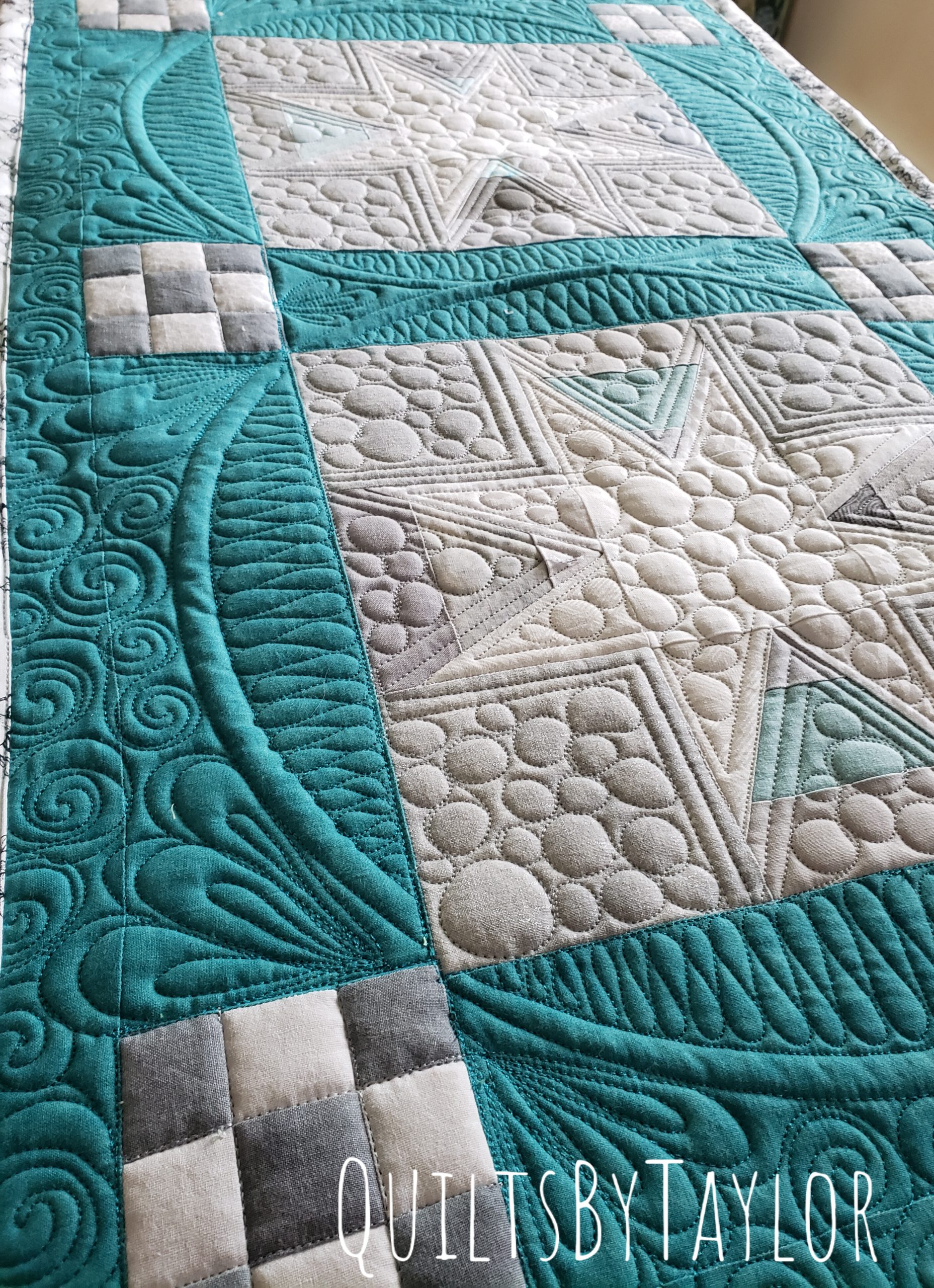 Modern quilted star table runner in teal and cream fabrics featuring custom free motion quilting and textured peble quilting.